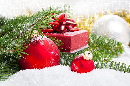带松枝、礼物和雪的红色圣诞球，在白色雪地上