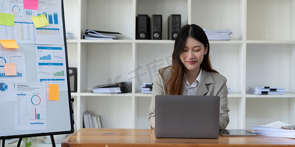 美丽的年轻亚洲女商人使用电脑笔记本电脑集中精力微笑