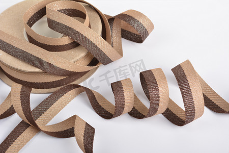 棕色米色棉质丝带，卷绕在线轴上的纺织品。