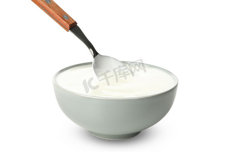白色背景中分离的一碗酸奶油酸奶和勺子