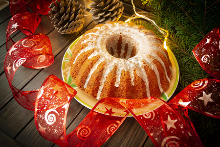 传统的自制圣诞蛋糕节日甜点在复古木桌背景的新年树装饰框架中。