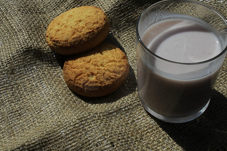 饼干酸奶摄影照片_饼干和一杯酸奶放在粗麻布材料上