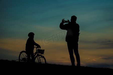 父母和孩子站在夕阳山上的剪影