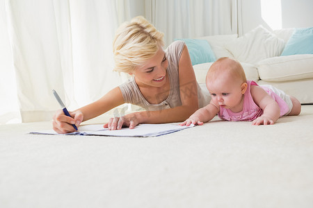 微笑的母亲和她的女婴在字帖上写字