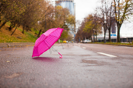 海滨城市图片摄影照片_户外湿沥青上的粉红色儿童伞