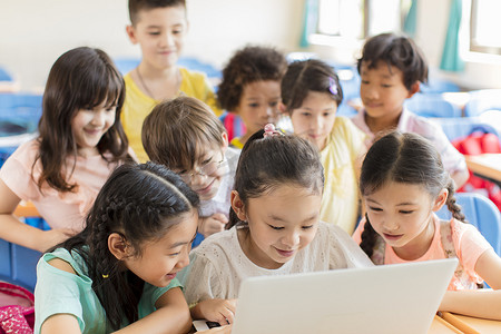 初等摄影照片_快乐的孩子们在教室里看笔记本电脑和讨论