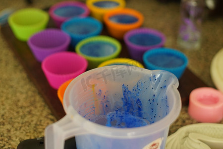 在塑料杯中融化肥皂并添加颜色和香料，然后倒入彩色硅胶模具中，制作自制的融化和倒肥皂