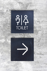 混凝土墙式精品店上的男女通用厕所或厕所和箭头标志
