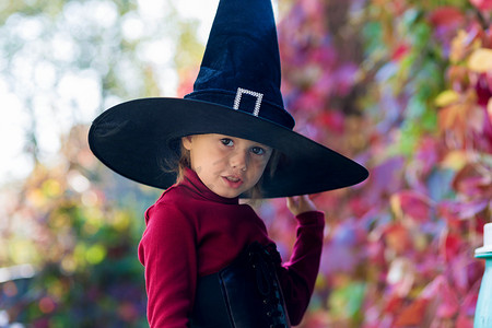 魔法师摄影照片_万圣节派对上穿着女巫服装的小女孩做出不同的面孔