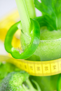 芹菜汁摄影照片_卷尺、西兰花、胡椒、芹菜和加芹菜汁的玻璃杯