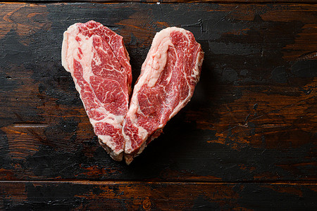 Love Raw Chuck Tenders 牛排配老式深色木桌有机牛肉。