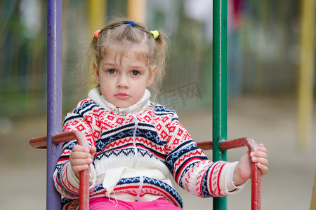 心烦意乱的四岁女孩骑在秋千上