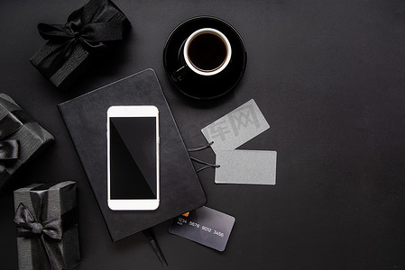 咖啡价格标签摄影照片_黑色智能手机、价格标签、咖啡和礼品在黑色背景中的顶视图