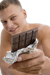 微笑的肌肉男展示巧克力