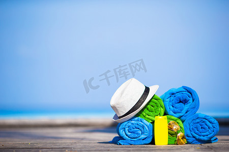 游泳镜摄影照片_海滩和暑假配饰概念 — 彩色毛巾、帽子、游泳镜和防晒霜的特写