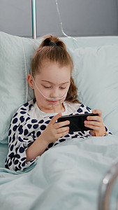 生病的小孩躺在床上用智能手机玩在线视频游戏