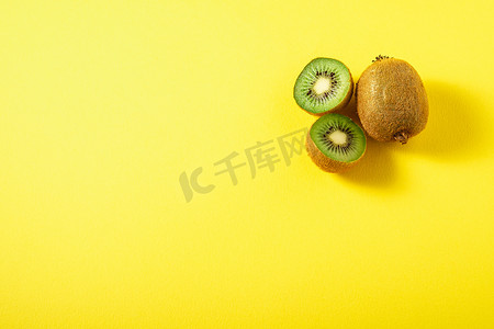 纯绿色背景摄影照片_在充满活力的纯黄色背景上切成一半的猕猴桃