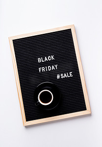 黑色背景宣传摄影照片_黑色字母板上的文本黑色星期五销售，白色背景上有一杯咖啡