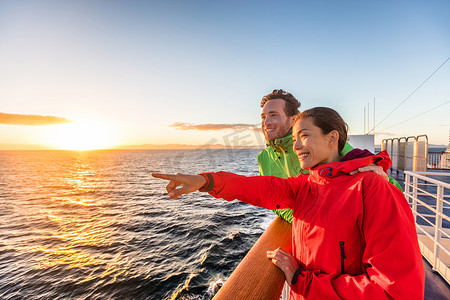 塞外之旅摄影照片_邮轮旅行的游客夫妇从渡轮之旅中指着海景。