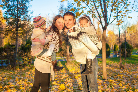 开心一家摄影照片_在阳光明媚的温暖日子里，一家四口在秋季公园玩得开心