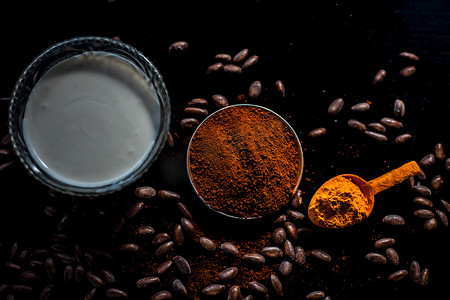 黑色光亮摄影照片_用于治疗油性皮肤和在由一些咖啡豆粉、姜黄粉和酸奶组成的黑色光亮表面上美白皮肤的咖啡面膜。