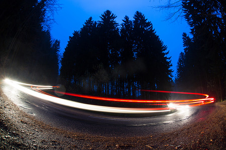 黄昏时分，汽车在森林公路上快速通过弯道