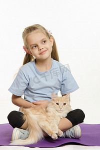 垫子摄影照片_坐在垫子上的体贴女孩，腿上有一只猫