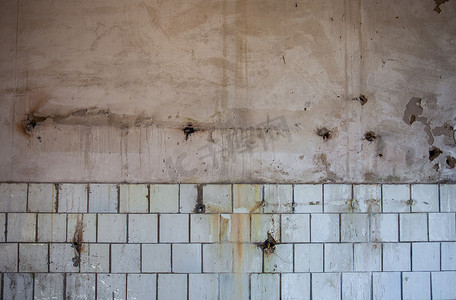 铺瓷砖摄影照片_旧的脏墙在顶部粉刷成白色，在底部铺瓷砖