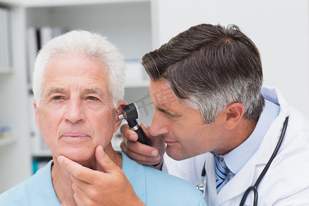老年镜摄影照片_医生用耳镜检查老年患者的耳朵