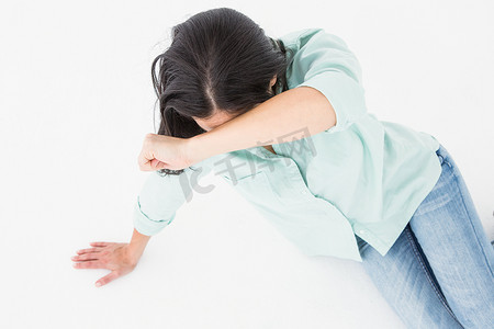 悲伤的女人坐在地板上，遮住脸