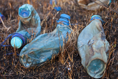 烧焦的草地上三个熔化的塑料瓶