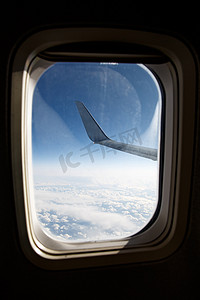 舷窗中蓝云上方的飞机机翼。