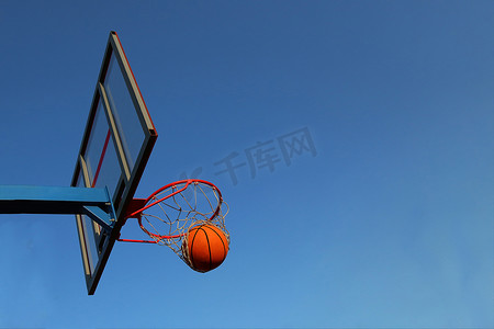 在室外篮球场上的篮子里打篮球。