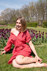 春天公园里一个穿红裙子的年轻美女玩弄头发，调情