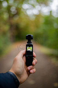 拿着 DJI Osmo 袖珍相机拍摄模糊森林的人像视图