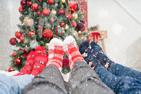 圣诞树背景下穿着圣诞袜躺在床上的人脚。