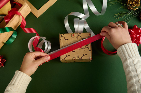 头顶的女人选择丝带来绑圣诞礼物，用鹿图案的包装纸包裹