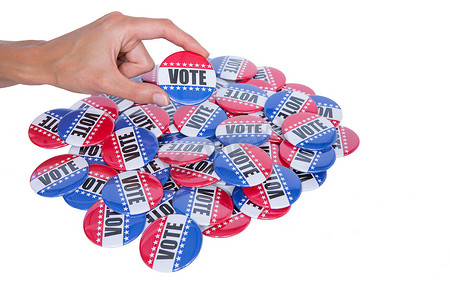 捐款公示霜手势摄影照片_在一堆徽章后面显示投票徽章的手