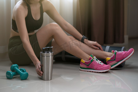 运动型女性在锻炼后休息，戴着蛋白质奶昔瓶