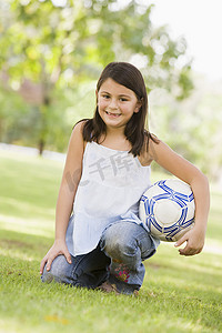 户外公园里的小女孩拿着球微笑