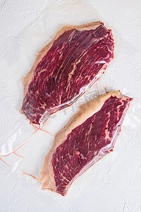 生 picanha 牛排真空包装有机牛肉肉在白色混凝土纹理背景，顶视图。