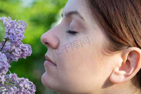 白种女人摄影照片_白种女人嗅着盛开的丁香花。