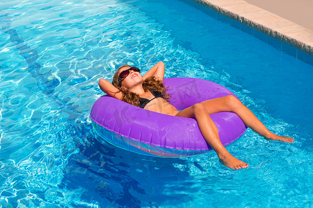 在紫色充气泳池环上放松的儿童女孩