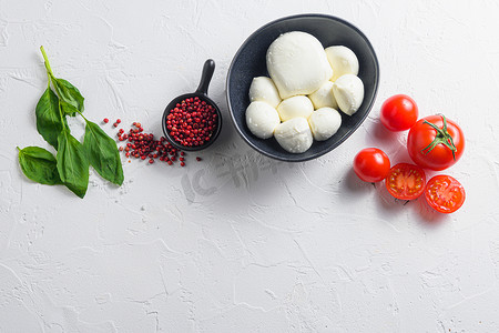 生熟的马苏里拉奶酪球，配上新鲜的罗勒叶和樱桃番茄，配料，在白色背景的顶视图空间中供文字