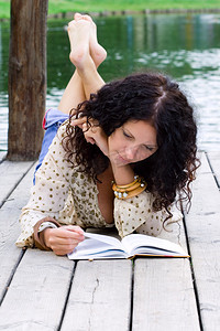 一个美丽的女人正在读书的户外肖像