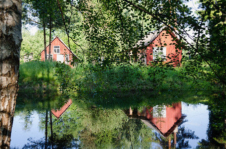 池塘树枝映照的红色乡村住宅