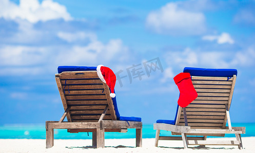 热带假期海滩躺椅上的红色圣诞帽和红色圣诞袜