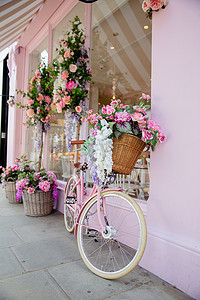 蛋糕店摄影照片_粉色蛋糕店外被人造花包围的粉色自行车