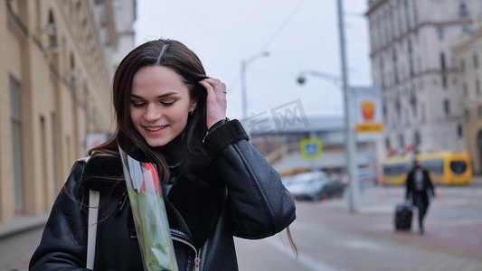 早春，一个穿着黑色夹克的快乐黑发女孩穿过城市。