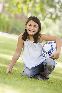 户外公园里的小女孩拿着球微笑